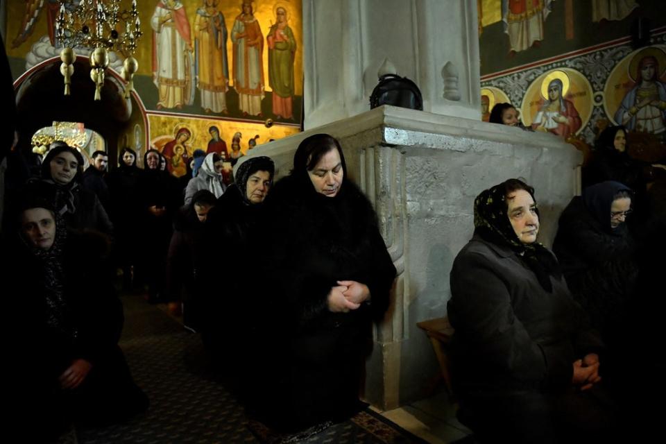 Local people pray during mass in the church at Putna monastery (Reuters)