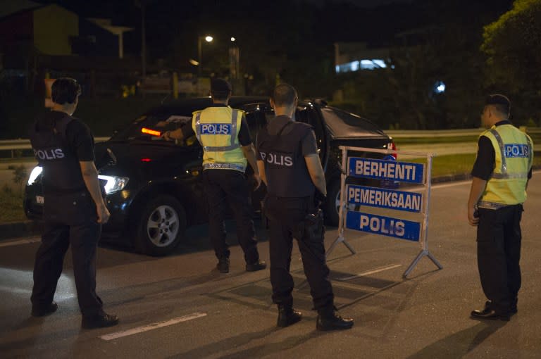 This picture taken in the early hours of August 21, 2013 shows policemen checking a vehicle at a roadblock during an operation in Kuala Lumpur. – AFP pic