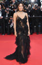 <p>wears a sheer black gown covered in delicate ruffles and sequins, which she complements with a jeweled ribbon choker necklace.</p>