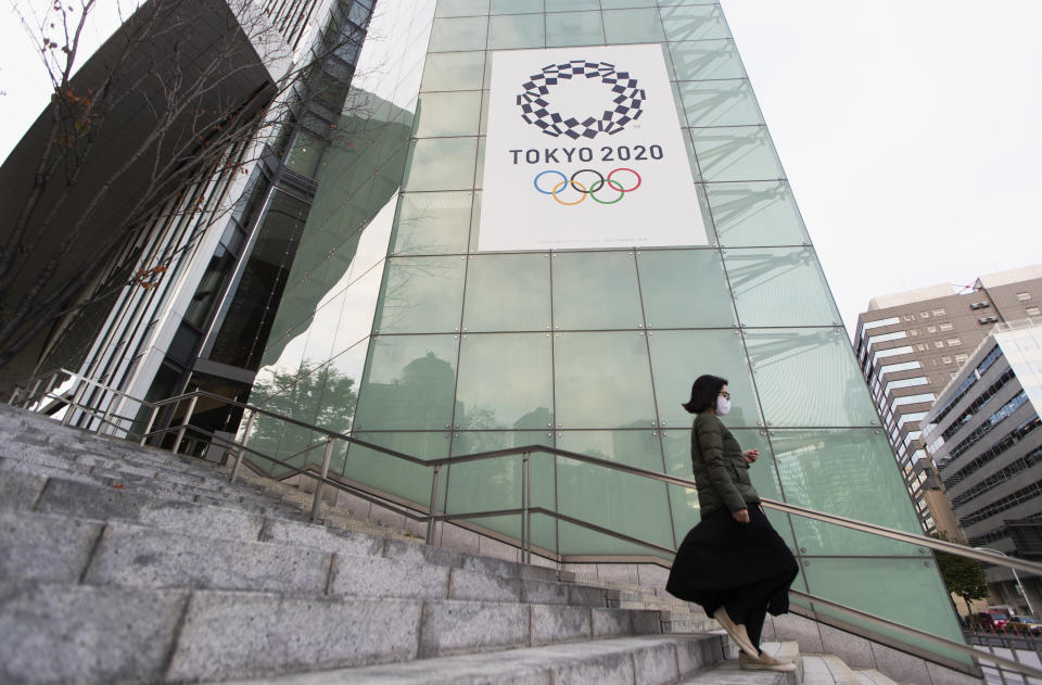 A woman walks by a sign to promote the Olympic and Paralympic games planned to start in the summer 2021, in Tokyo on Thursday, Nov. 12, 2020. The postponed Tokyo Olympics are to open in just under nine months. The International Olympic Committee and Japanese organizers have unwavering support from Japan’s ruling party and Tokyo’s municipal government. But there is a tiny murmur of resistance to the Olympic behemoth. A few voices in the national legislature question the wisdom of holding the Olympics in a pandemic.(AP Photo/Hiro Komae)