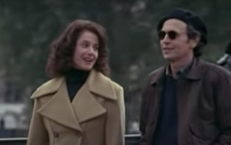 Debra Winger wears a peacoat and walks alongside Billy Crystal who wears sunglasses and a hat.