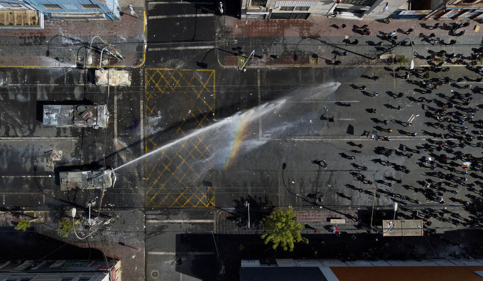 In this Oct. 26, 2019 photo, a police water cannon sprays anti-government demonstrators in Valparaiso, Chile. Clashes broke out Saturday as demonstrators returned to the streets, dissatisfied with economic concessions announced by the government in a bid to curb a week of deadly violence. (AP Photo/Matias Delacroix)
