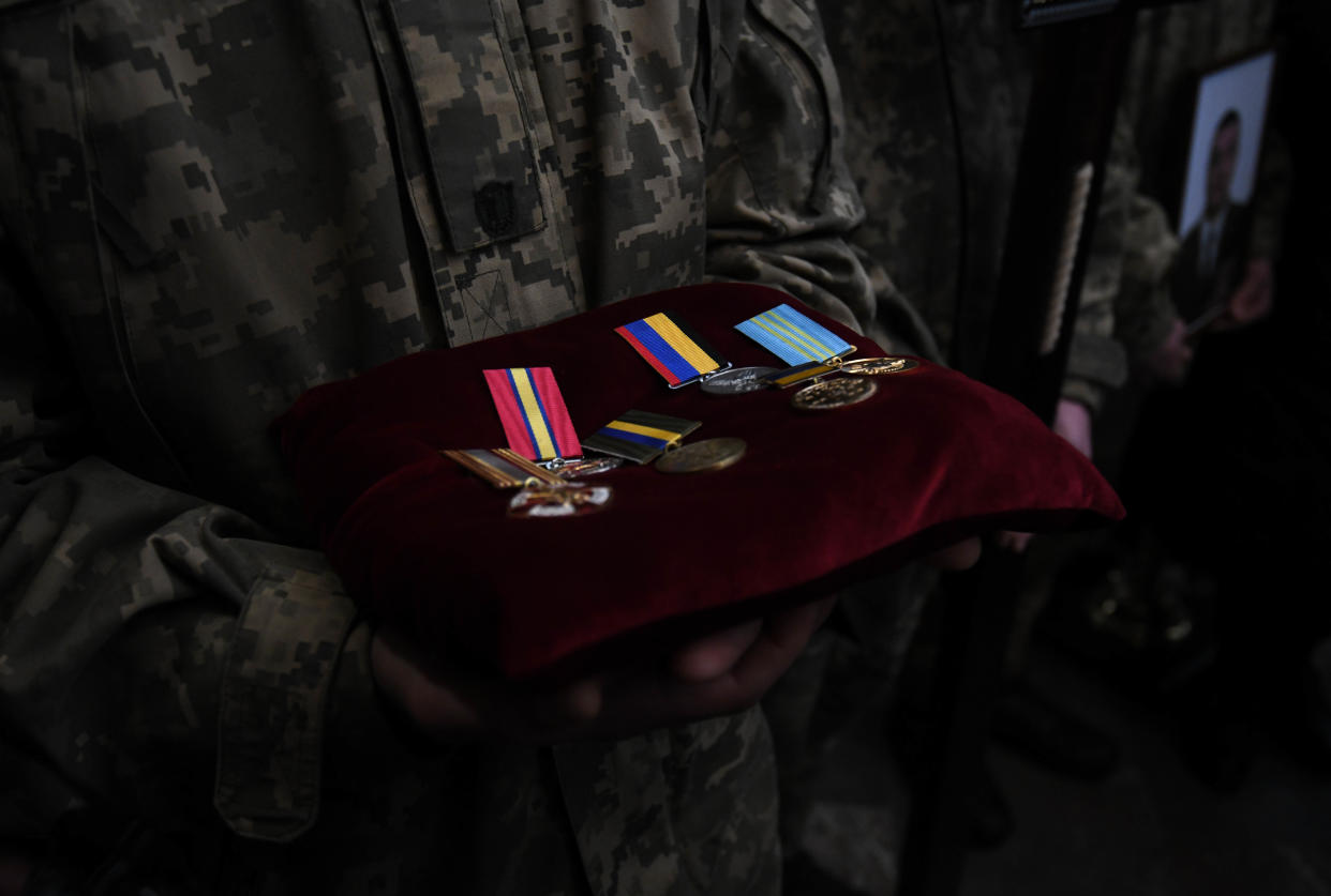 A Ukrainian soldier displays medals on a velvet cushion.