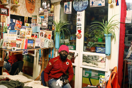 Samuel Pieta, 33, holds his cat in his apartment room in one of the four occupied buildings by migrants of the former Olympic village in Turin Italy January 8, 2018. Picture taken January 8, 2018. REUTERS/Siegfried Modola