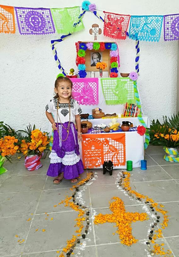 Carli Pierson's daughter dressed in traditional folkloric clothes from the state of Campeche, Mexico, at her school's Day of the Dead celebration in 2018. The picture on the altar is of Maria Montessori.