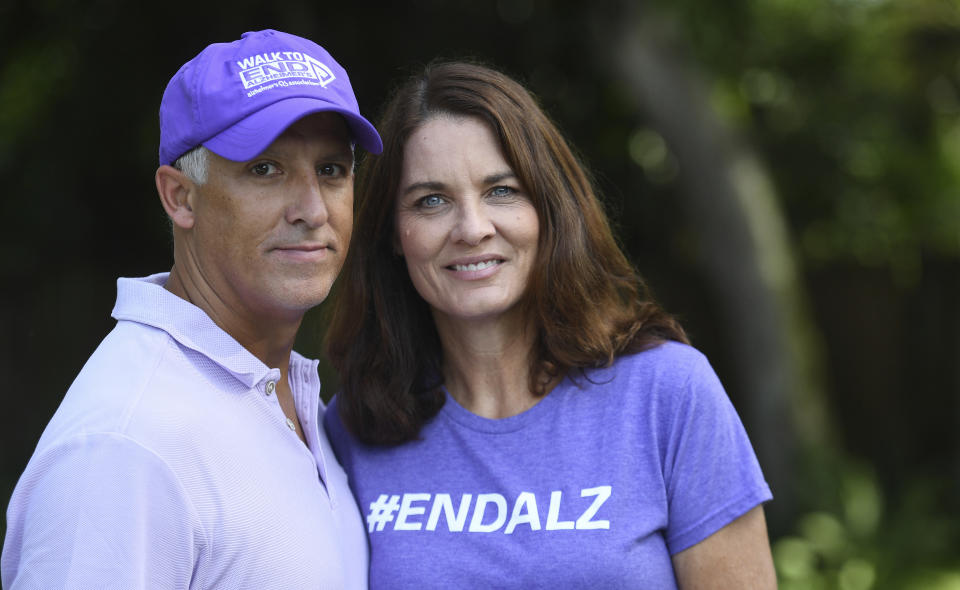 Michele Hall stands with her husband, Doug, in their backyard Thursday, June 24, 2021, in Bradenton, Fla. Hall, 54, diagnosed with early Alzheimer's last year, calls the new drug Aduhelm "the first tiny glimmer of hope" she'll get more quality time with her husband and their three adult children. (AP Photo/Steve Nesius)
