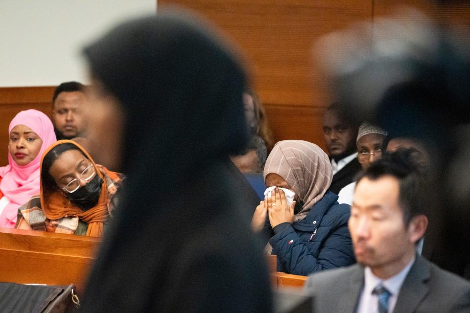 Shukri Hassan, the daughter of Imam Mohamed Hassan Adam, speaks as a member of the audience wipes away tears during the victim impact portion of the sentencing Thursday, March 7, 2024, for his convicted killer, 48-year-old John Wooden Jr.