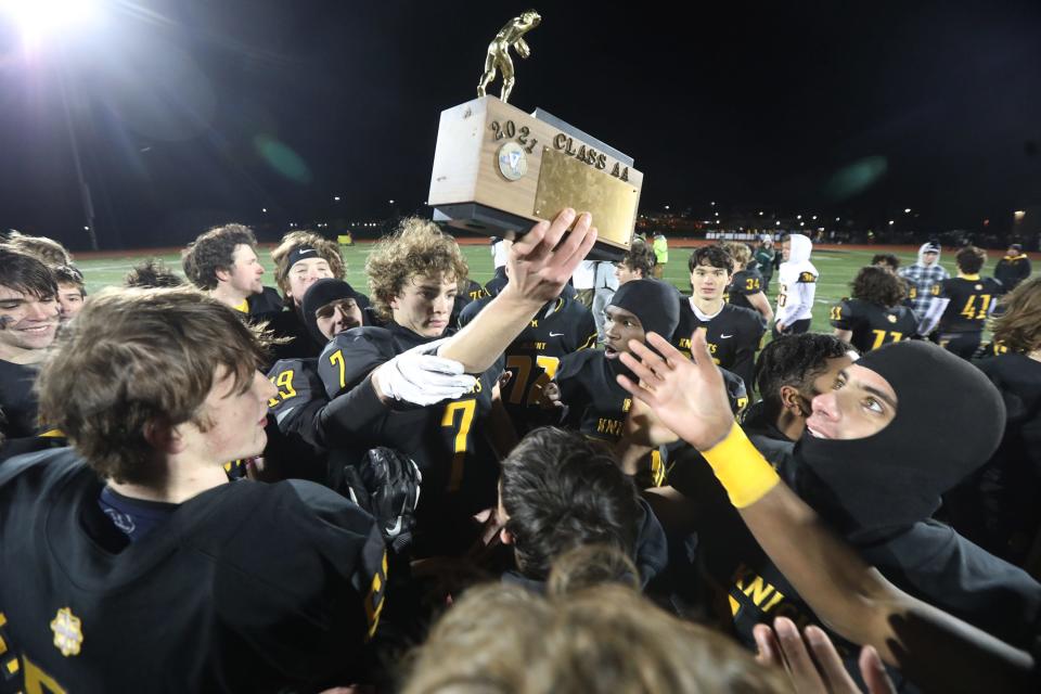 McQuaid's Anthony Dimarco holds up the Class AA trophy and passes it off to another player. Players grabbed and kissed the trophy after McQuaid's 28-14 win over Aquinas in the Section V Class AA final.