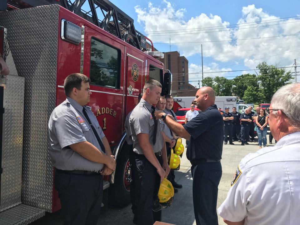 Mansfield police Capt. Rob Garn pins a badge on his son Michael Garn during a previous swearing-in ceremony of five new firefighters at the Mansfield Fire Department.