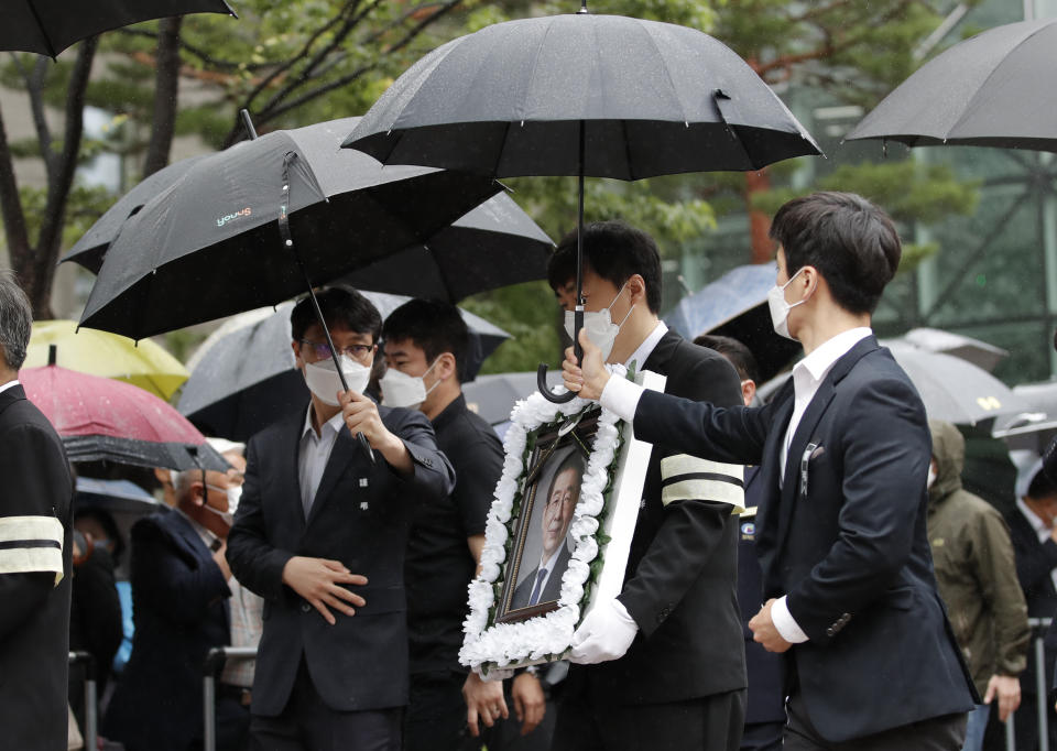 A man carries a portrait of late Seoul Mayor Park Won-soon after his official funeral outside the Seoul City Hall in Seoul, South Korea, Monday, July 13, 2020. Masked mourners gave speeches and laid flowers before the coffin of Seoul's mayor during his funeral Monday, while a live broadcast online drew a mixture of condolence messages and insults.(AP Photo/Lee Jin-man)