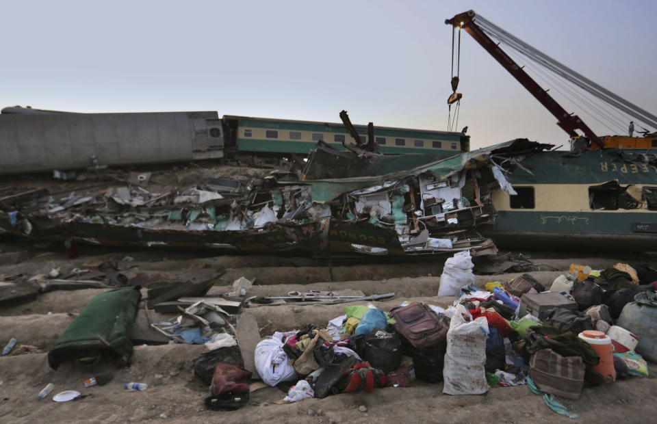 Railway workers use crane to clear the track at the track at the site of a train collision in the Ghotki district, southern Pakistan, Monday, June 7, 2021. An express train barreled into another that had derailed in Pakistan before dawn Monday, killing dozens of passengers, authorities said. More than 100 were injured, and rescuers and villagers worked throughout the day to search crumpled cars for survivors and the dead. (AP Photo/Fareed Khan)