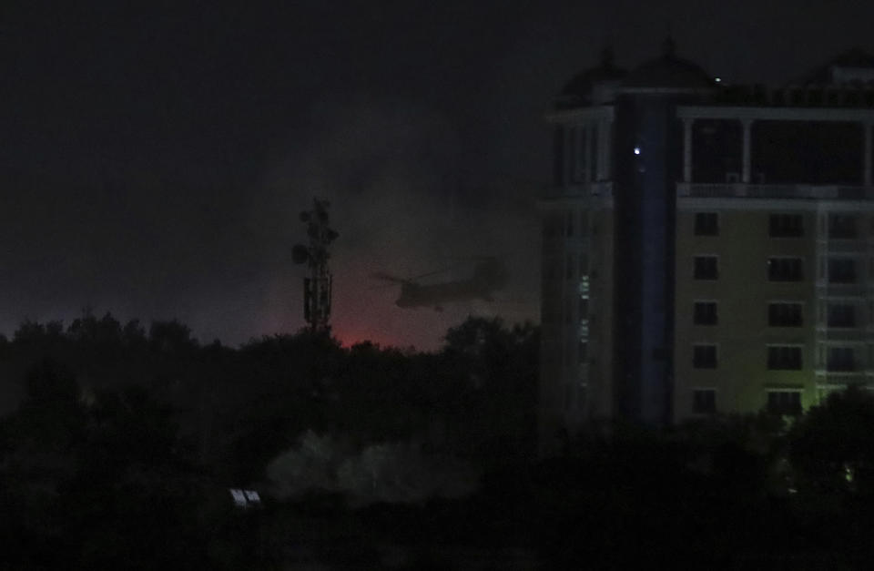 A U.S. Chinook helicopter flies near the U.S. Embassy as smoke rises in Kabul, Afghanistan, late Sunday, Aug. 15, 2021. (AP Photo/Rahmat Gul)