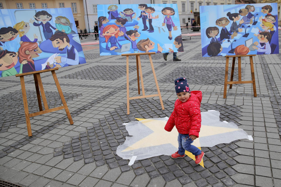 A child walks by boards depicting the creation of the Bucharest EU Children Declaration, a call for EU leaders to make child participation a priority, by children supported by UNICEF in the Piata Mare square in the Transylvanian town of Sibiu, Romania, Wednesday, May 8, 2019. European Union leaders hold an EU summit in Sibiu on Thursday to start setting out a course for increased political cooperation in the wake of the impending departure of the United Kingdom from the bloc. (AP Photo/Vadim Ghirda)