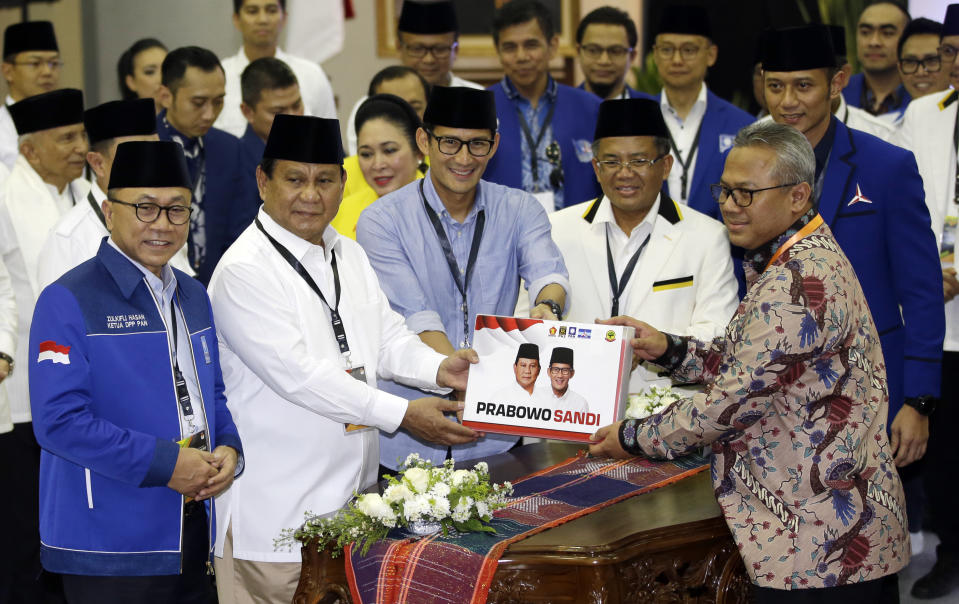 Indonesian presidential candidate Prabowo Subianto, second left, and his running mate Sandiaga Salahuddin Uno, center right, give a folder of formal registration as candidates for the 2019 presidential election to Head General Election Commission Arief Budiman, front right, in Jakarta, Indonesia. Friday, Aug. 10, 2018. Prabowo is running with businessman and deputy Jakarta governor Sandiaga Uno. Both officially registered as candidates after Friday prayers. (AP Photo/Achmad Ibrahim)