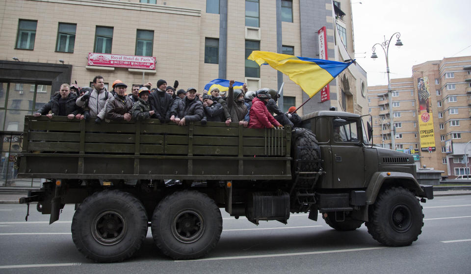 Protesters ride atop of what appears to be a military truck, in central Kiev, Ukraine, Saturday, Feb. 22, 2014. Protesters in the Ukrainian capital claimed full control of the city Saturday following the signing of a Western-brokered peace deal aimed at ending the nation's three-month political crisis. The nation's embattled president, Viktor Yanukovych, reportedly had fled the capital for his support base in Ukraine's Russia-leaning east. (AP Photo/Darko Bandic)