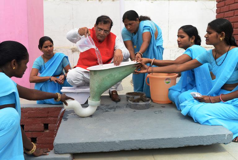 Founder of Indian sanitation charity Sulabh International Bindeshwar Pathak (C) demonstrates his low-cost two-pit toilet technology in New Delhi