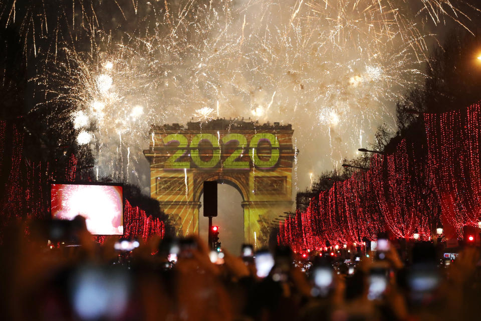 Revellers photograph fireworks over the Arc de Triomphe as they celebrate the New Year on the Champs Elysees, in Paris, France, Wednesday, Jan. 1, 2020. (AP Photo/Christophe Ena)