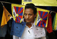 FILE - A Tibetan exile looks out from a tent at a protest rally to mark the end of the Beijing Olympics in New Delhi, India on Aug. 24, 2008. The 2022 Beijing Winter Olympics open in just over a week. When Beijing held the Summer Olympics in 2008 the International Olympic Committee predicted they could improve human rights, and Chinese politicians hinted at the same. There are no soaring promises this time. (AP Photo/Mustafa Quraishi, File)