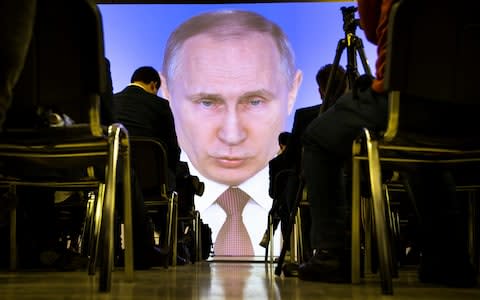 Journalists watch as Russian President Vladimir Putin gives his annual state of the nation address in Manezh in Moscow - Credit: AP