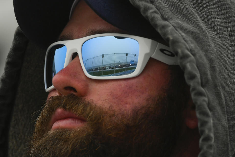 A track fence and lights on pit row are reflected in a fan's glasses as he watches the NASCAR Xfinity auto race at Atlanta Motor Speedway, Saturday, Feb. 23, 2019, in Hampton, Ga. (AP Photo/John Amis)