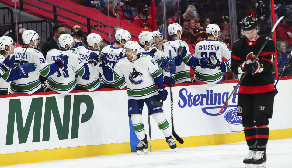 Vancouver Canucks center Tyler Motte (64) celebrates a goal with teammates on the bench as Ottawa Senators center Adam Gaudette (17) makes his way up ice during the second period of an NHL hockey game, Wednesday, Dec.1, 2021 in Ottawa, Ontario. (Sean Kilpatrick/The Canadian Press via AP)