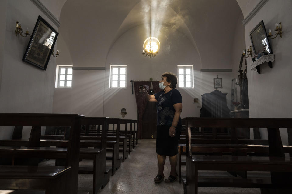 Parishioner Maria Tsagorari holds an incense burner inside the Dormition of the Virgin Mary Catholic Church on the Greek island of Santorini on Wednesday, June 15, 2022. Before coronavirus restrictions, she used to attend Mass regularly at the Monastery of St. Catherine, where cloistered nuns have lived for more than four centuries. (AP Photo/Petros Giannakouris)
