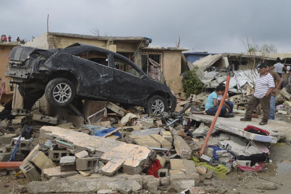 Residents stand outside their damaged house after a tornado hit the town of Ciudad Acuna