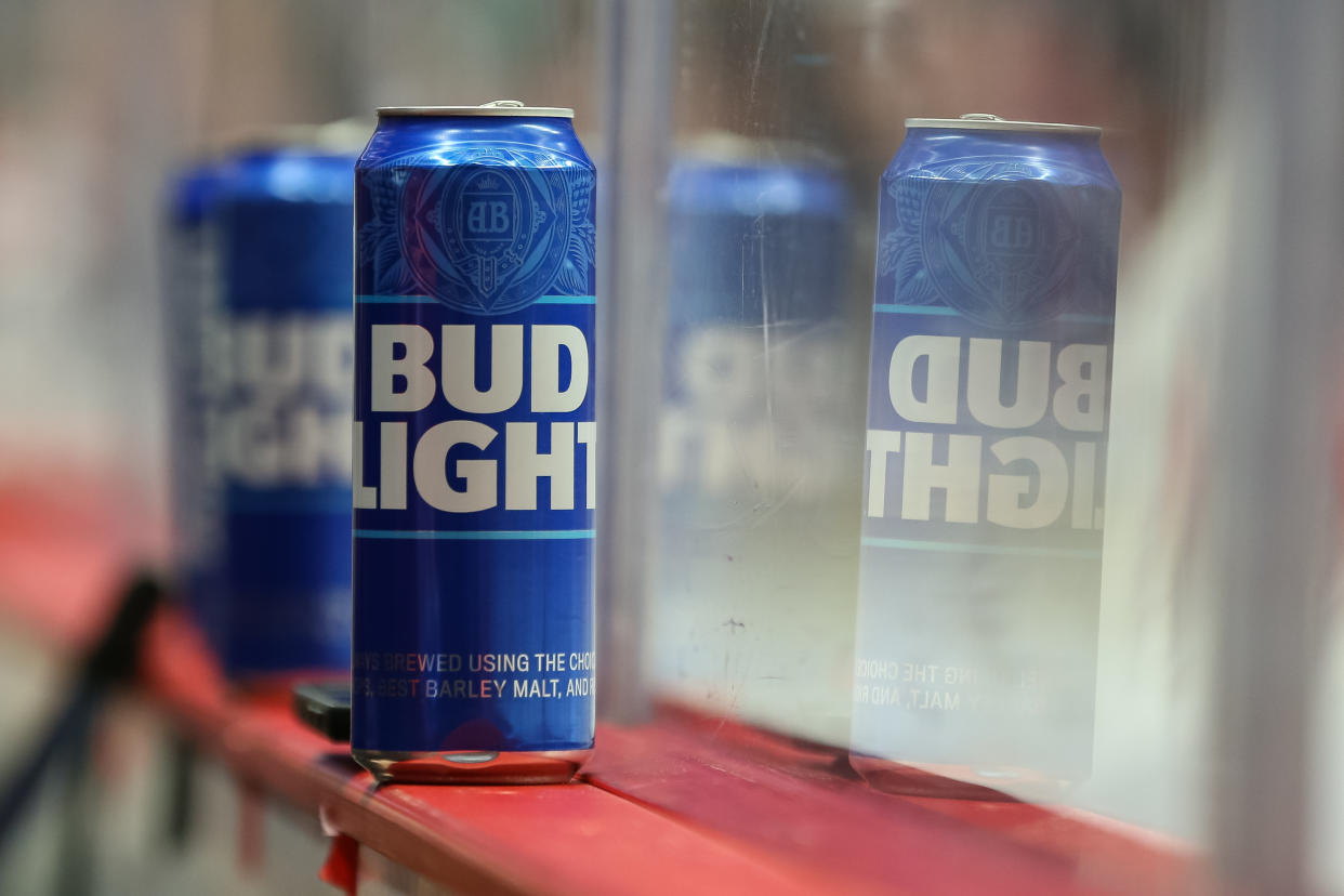 Bud Light beer cans sit on a ledge at a hockey arena.