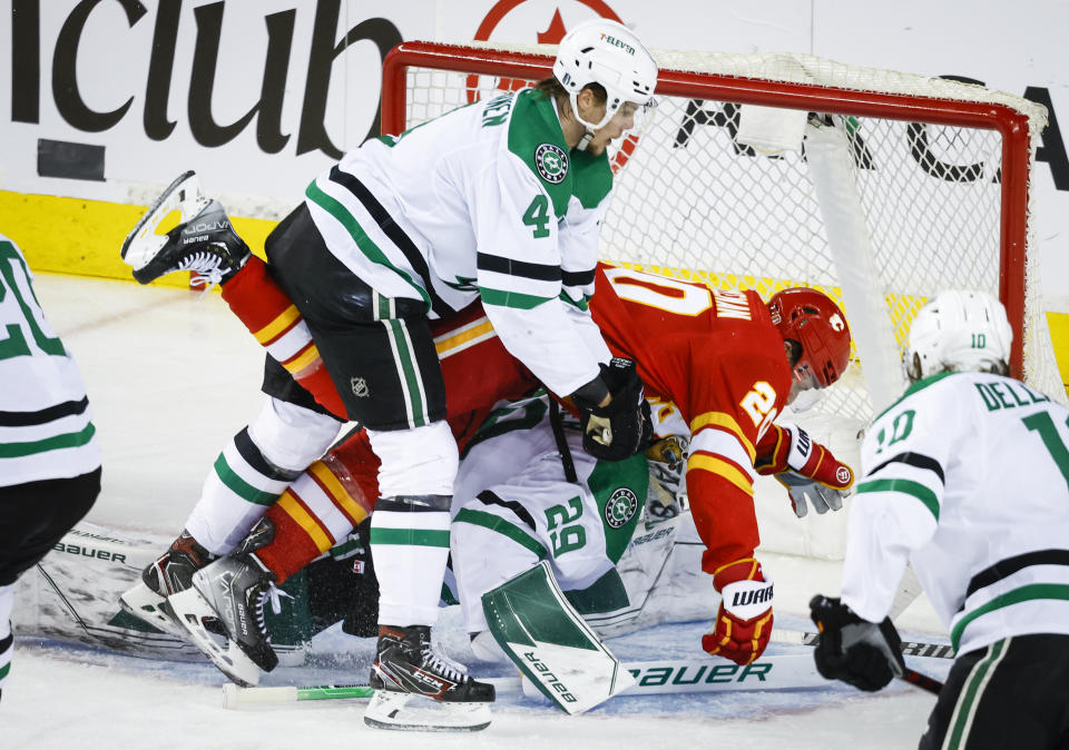 Dallas Stars defenseman Miro Heiskanen, left, checks Calgary Flames forward Blake Coleman, right, into goalie Jake Oettinger during second period NHL playoff hockey action in Calgary, Alberta, Sunday, May 15, 2022. (Jeff McIntosh/The Canadian Press via AP)