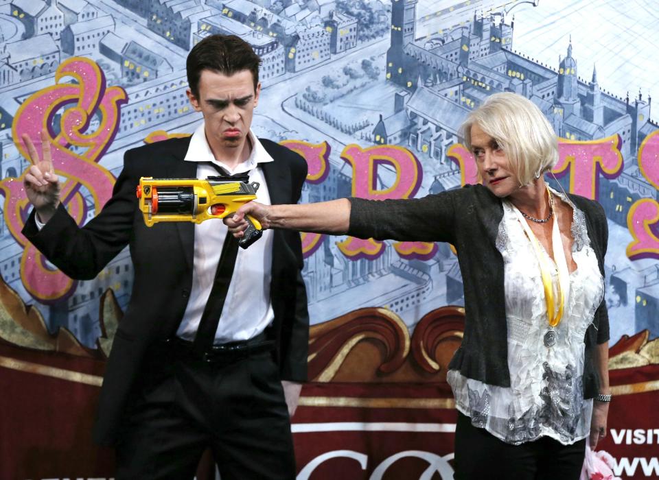 Actress Helen Mirren fires a toy gun next to actor Sam Clark who plays an Al Pacino character during her roast as woman of the year by Harvard University's Hasty Pudding Theatricals in Cambridge, Mass., Thursday, Jan. 30, 2014. (AP Photo)