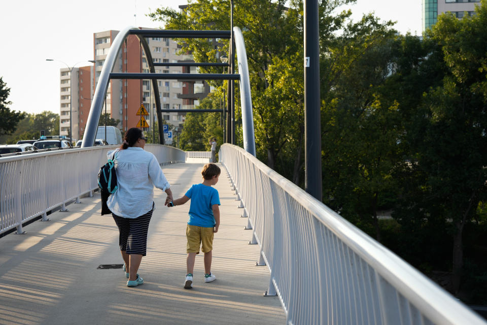 A woman is seen walking while holding hands with a boy on a bridge in Warsaw, Poland on 26 August, 2022. (Photo by STR/NurPhoto via Getty Images)