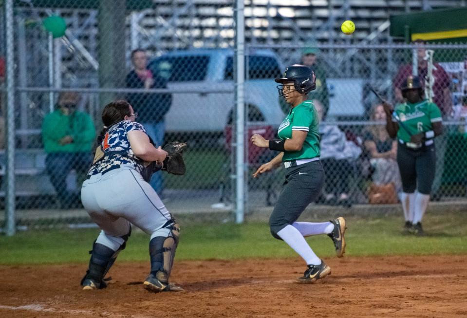 Morgan Smith (11) safely takes home as the throw hits her in the back giving the Crusaders a 2-0 lead during the Escambia vs Catholic softball game at Pensacola Catholic High School on Friday, April 28, 2023.