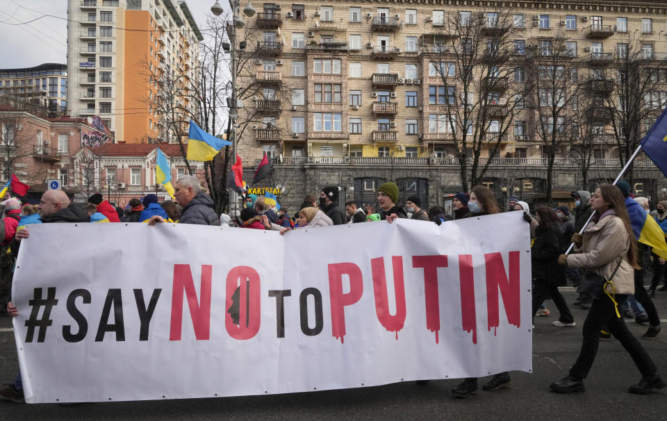 File - Ukrainians attend a rally in central Kyiv, Ukraine, Feb. 12, 2022, during a protest against the potential escalation of the tension between Russia and Ukraine. German Chancellor Olaf Scholz planning to travel to Ukraine and Russia on Monday, Feb. 14, 2022, in an effort to help defuse escalating tensions as Western intelligence officials warn that a Russian invasion of Ukraine is increasingly imminent. (AP Photo/Efrem Lukatsky, File)