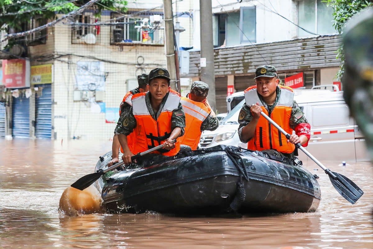 Paramilitary policemen search an area after it was flooded by heavy rains in China’s southwestern Chongqing on 4 July  (AFP via Getty Images)