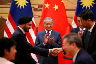 Malaysia's Prime Minister Mahathir Mohamad and China's Premier Li Keqiang clap as delegates exchange documents during a signing ceremony at the Great Hall of the People in Beijing, China, August 20, 2018. How Hwee Young/Pool via REUTERS