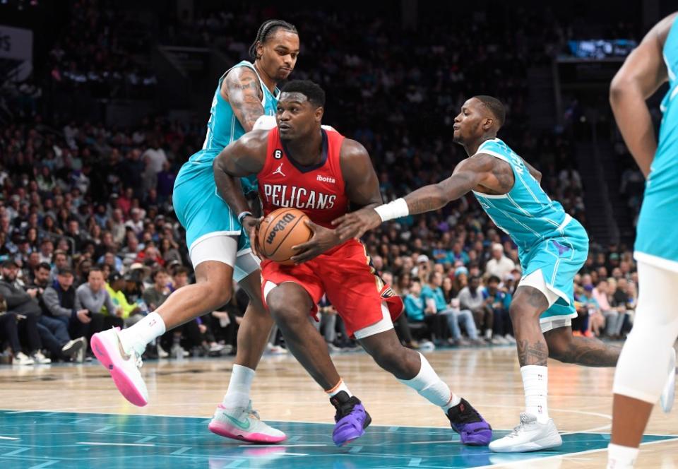 Zion Williamson driving the ball against two Hornets players