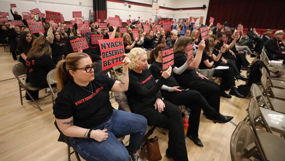 Nyack teachers and other union school workers hold up "Nyack Deserves Better" signs at the Nyack school board meeting at Nyack Middle School, March 19, 2024.