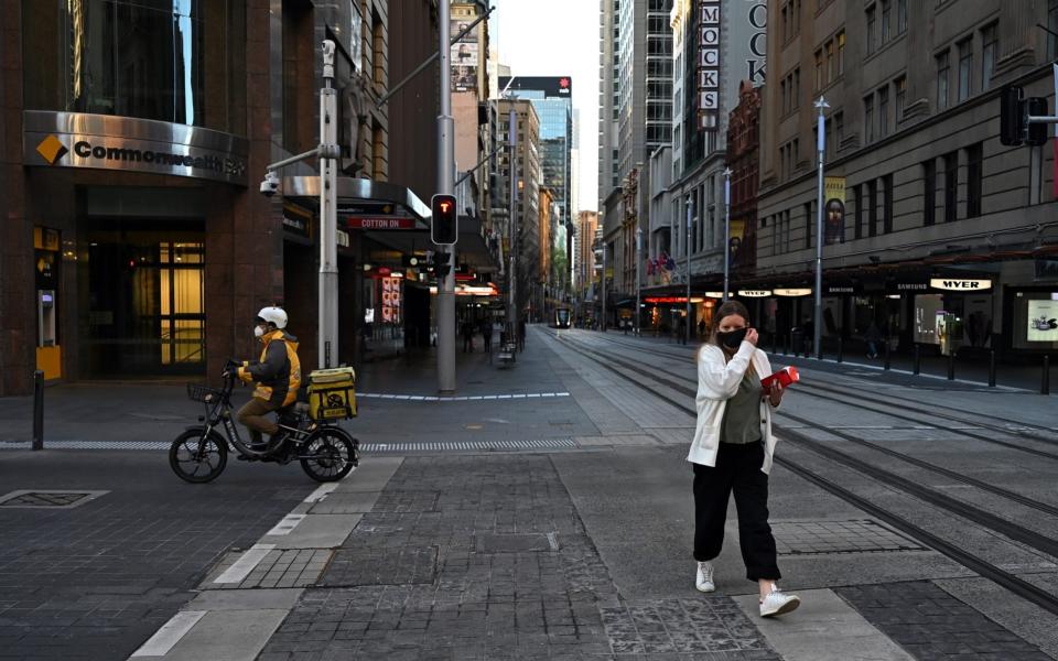 A woman crosses the street as a delivery rider drives past in the Sydney CBD, Australia on September 16, 2021. ( - Anadolu