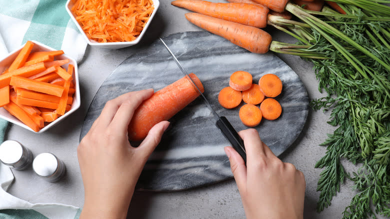 Hands cutting carrots on marble