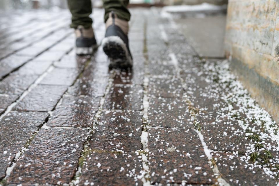 Person walking on salted, icy brick sidewalk.