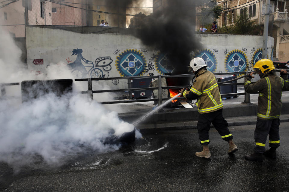 Firefighters extinguish burned tires that were set on fire to block a road during a demonstration, in Beirut, Lebanon, Sunday, Sept. 29, 2019. Hundreds of Lebanese are protesting an economic crisis that has worsened over the past two weeks, with a drop in the local currency for the first time in more than two decades. (AP Photo/Bilal Hussein)