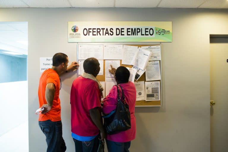 People scan the bulletin board for job postings at the unemployment office in San Juan, Puerto Rico