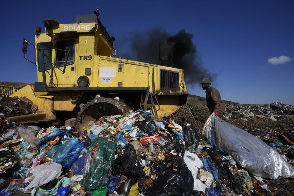 A waste picker rummages through garbage, at a dumping site in Johannesburg, South Africa, Friday, May 20, 2022. Environmental activists are gathering in South Africa this week to press governments and businesses to reduce the production of plastic because it is harming the continent’s environment. (AP Photo/Themba Hadebe)