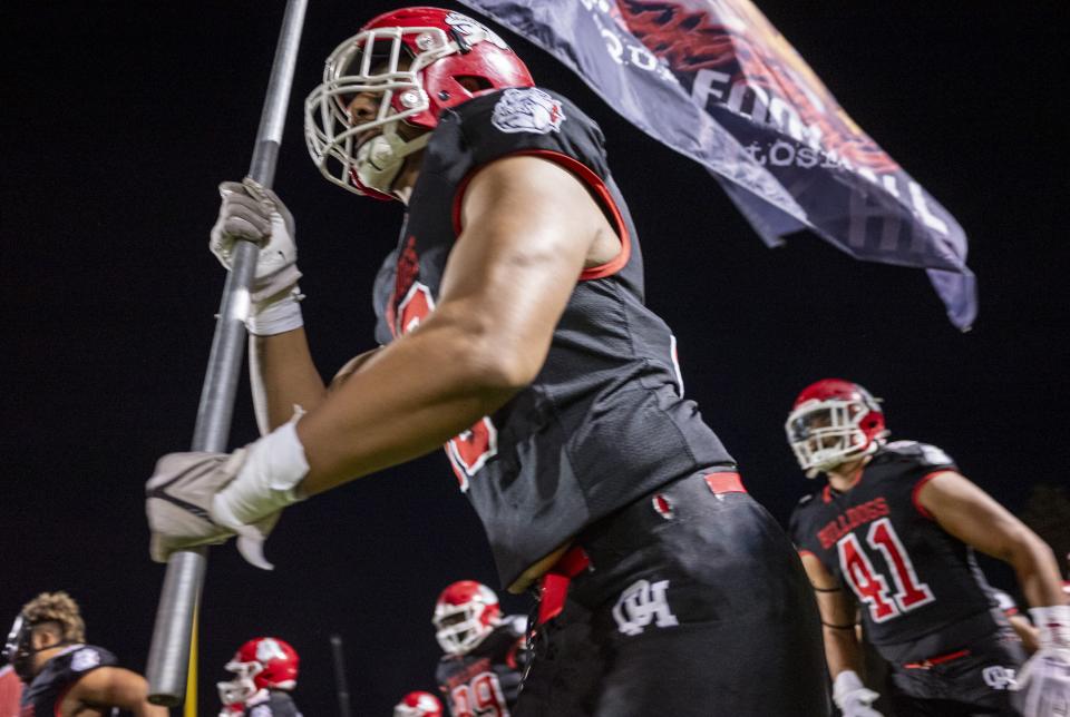 An Oak Hills player carries out a flag before taking the field on Friday, Oct. 13, 2023. Oak Hills won the game 42-21 to close in on capturing the Mojave River League title for a third straight season.