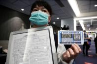 An airport staff holds up information boards regarding passenger health declaration and home quarantine information a mandatory form to fill up once land in Taiwan at Songshan airport in Taipei,
