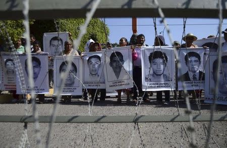 Relatives hold up pictures of some of the 43 missing students of Ayotzinapa College Raul Isidro Burgos during a protest outside at the 27th Infantry Battalion, in Iguala, southern Mexican state of Guerrero, December 18, 2014. REUTERS/Emiliano Torres