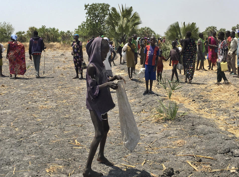 FILE - In this Wednesday, March 1, 2017 file photo, Lulu Yurdio, 12, collects food aid for himself and his two siblings and parents who remain hiding in the bush, in Padeah, South Sudan. Five months into South Sudan's fragile peace deal and 1.5 million people are on the brink of starvation while half the population, more than six million people are facing extreme hunger, according to a report released Friday Feb. 22, 2019, by the United Nations and South Sudan's government. (AP Photo/Sam Mednick, File)