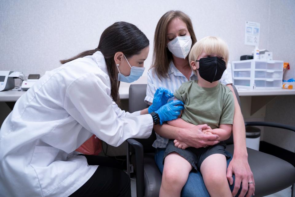 Pharmacist Kaitlin Harring, left, administers a Moderna COVID-19 vaccination to three-year-old Fletcher Pack, while he sits on the lap of his mother, McKenzie Pack, at Walgreens pharmacy, on June 20, 2022, in Lexington, S.C.