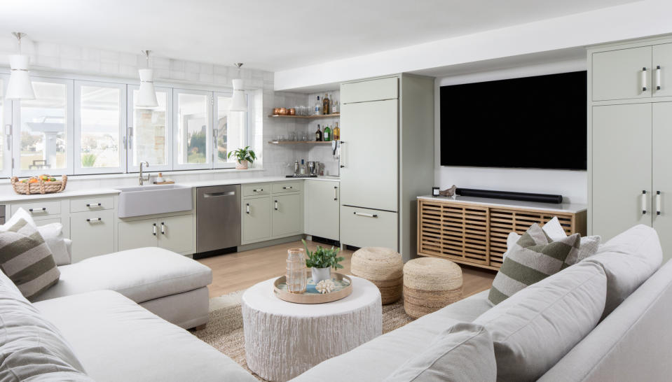 basement room with large sofa, tv, and kitchen area