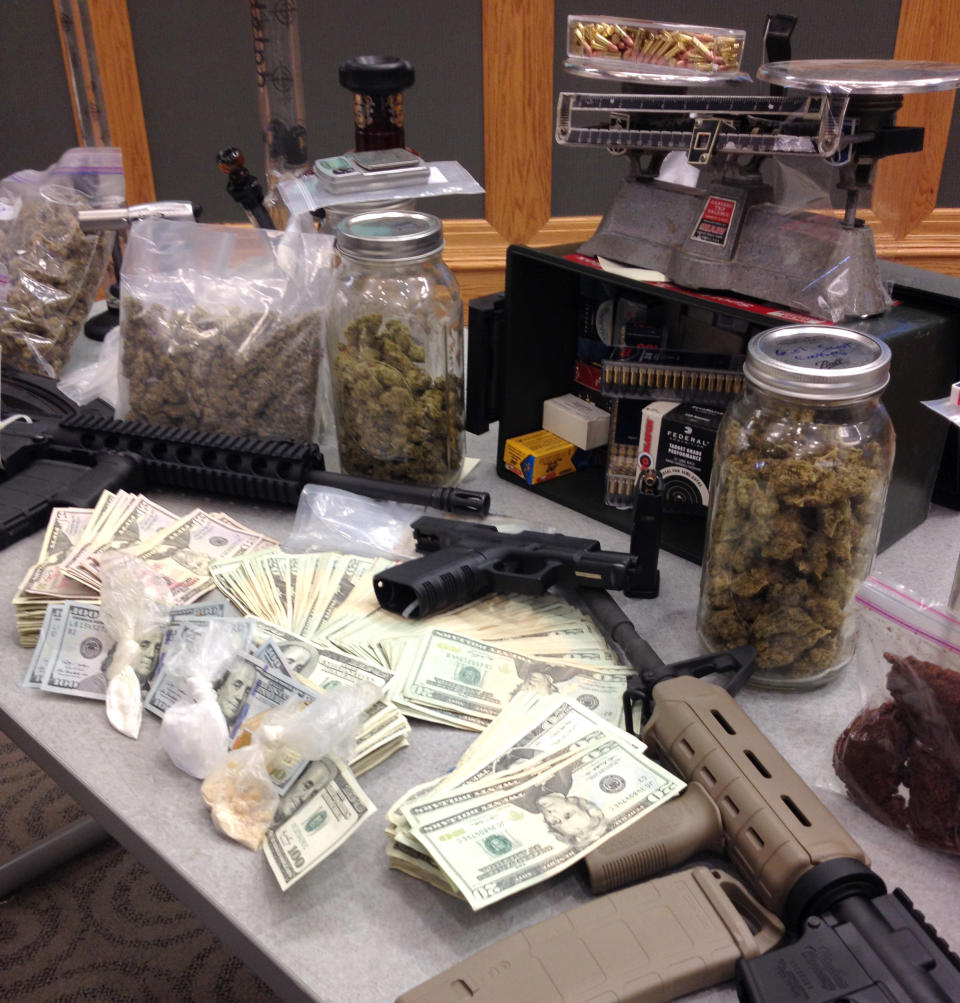 Stacks of cash and semi-automatic weapons are displayed on a table with suspected drugs and dealing equipment during a news conference on Monday, April 21, 2014 in, Ardmore, Pa. Montgomery County allege the leaders of a drug ring operation are 25-year-old Neil Scott and 18-year-old Timothy Brooks, both graduates of The Haverford School. (AP Photo/Kathy Matheson)